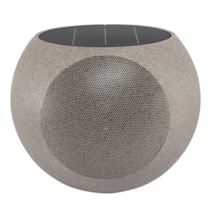 Victrola Zen Premium Solar Garden Speaker in stone finish placed in a garden layout